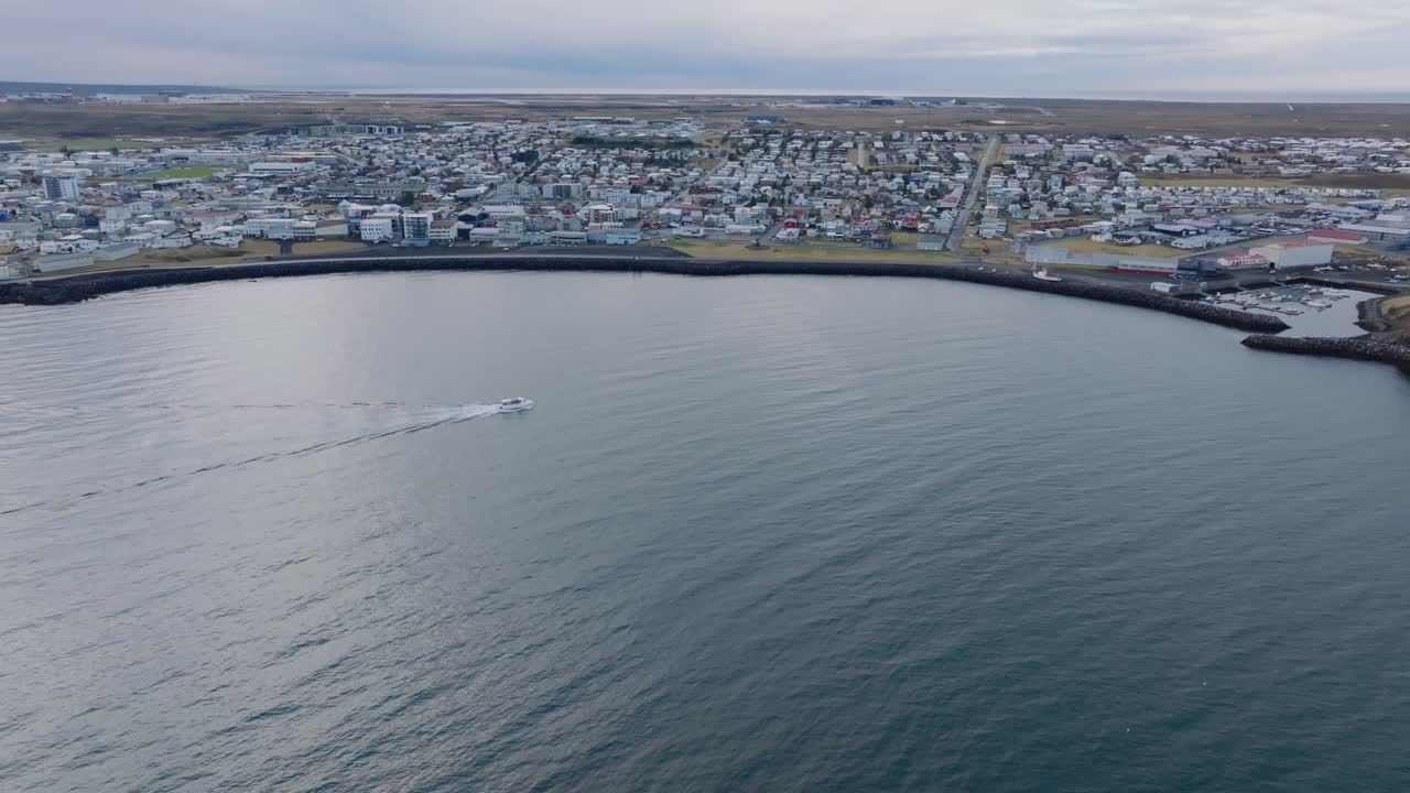 Barca che naviga nelle calme acque islandesi, porto di Keflavik sullo sfondo - 4K aereo