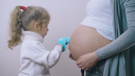 chica con botas azules de bebé en las manos abraza a la mamá embarazada