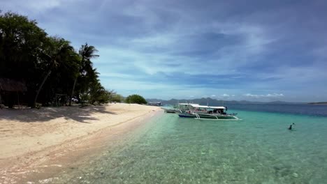 Fpv-drone-shot-along-tour-boats-moored-in-Turquoise-water-beach-shoreline-in-Coron,-Palawan