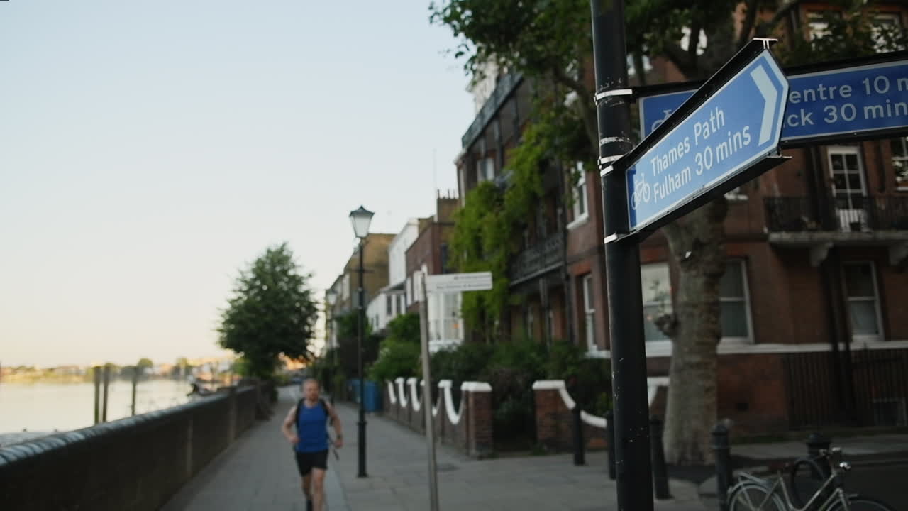 Athletic man running on path along Thames River, London, slow motion