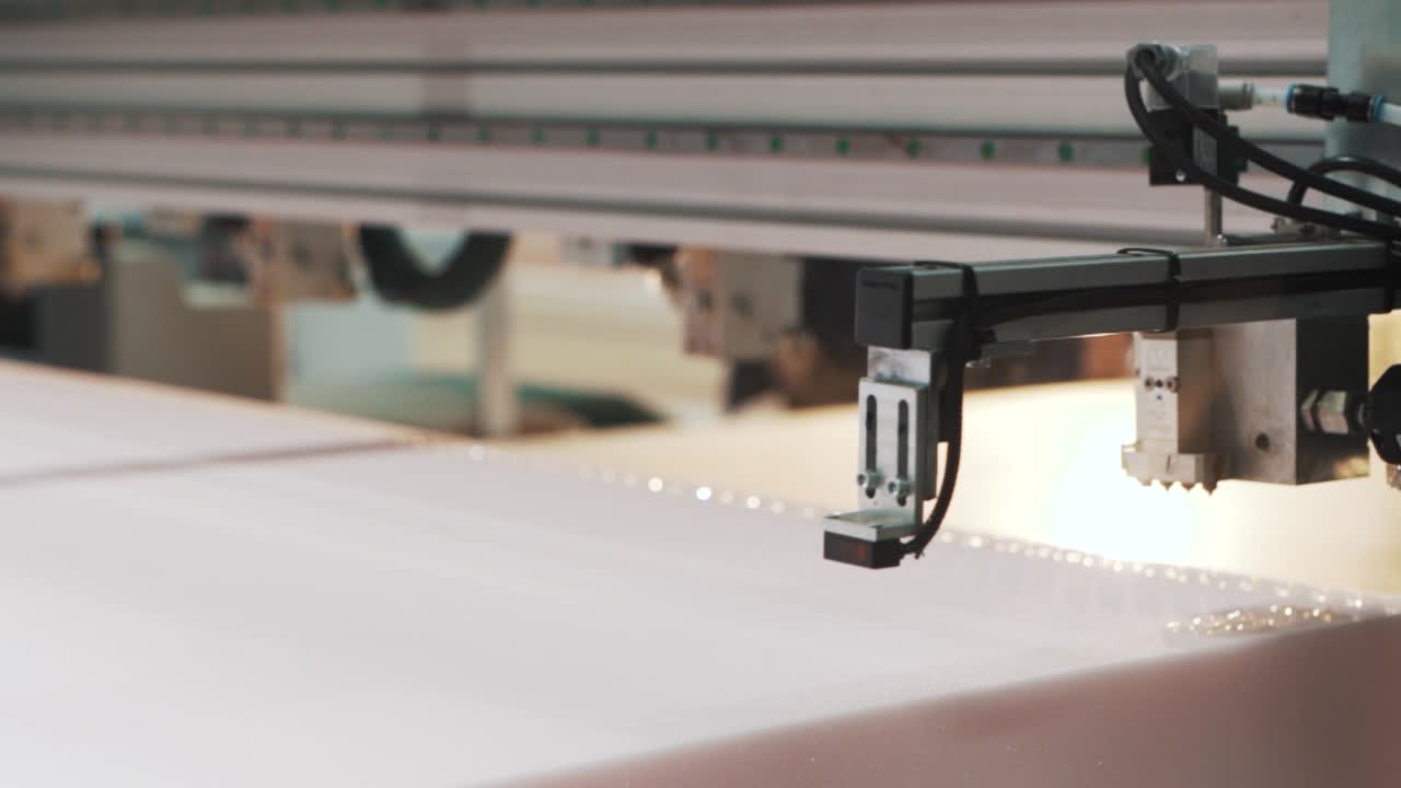 close-up de uma máquina de fábrica aplicando automaticamente cola ao material para fazer um colchão em uma produção têxtil