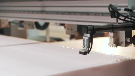 close-up-shot-of-a-factory-machine-automatically-applying-glue-to-the-material-for-making-a-mattress-in-a-textile-production