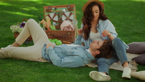 hombre encantador acostado en la pierna de la mujer al aire libre. pareja pasando tiempo en un picnic