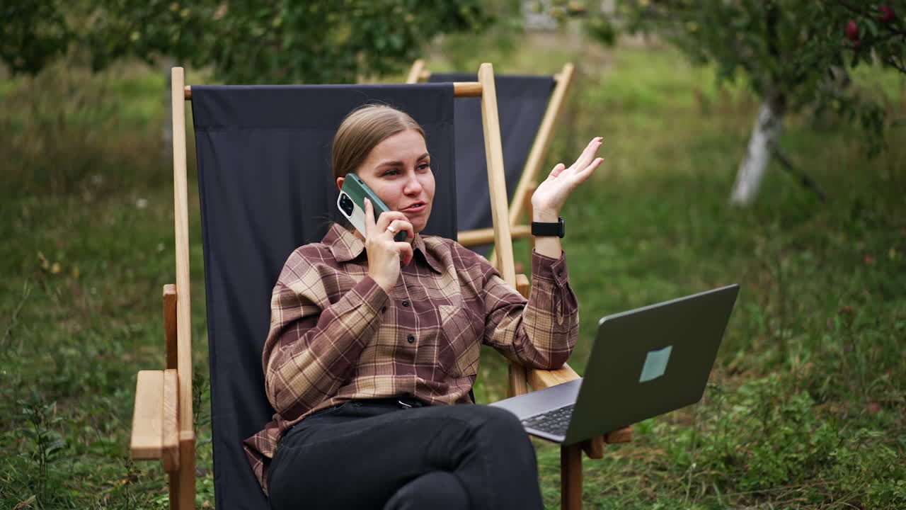 Woman working outdoors with laptop and phone