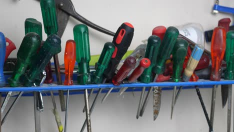 slow panning clip of messy work space shelf with screwdrivers hanging in a workshop