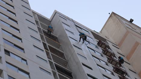 trabajadores limpiando ventanas en un edificio alto