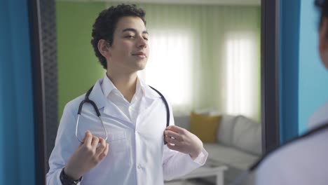 cute boy looking at himself in front of the mirror dressed as a doctor at home. future doctor.