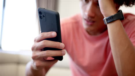 a young biracial upset and stressed man is focused on his smartphone