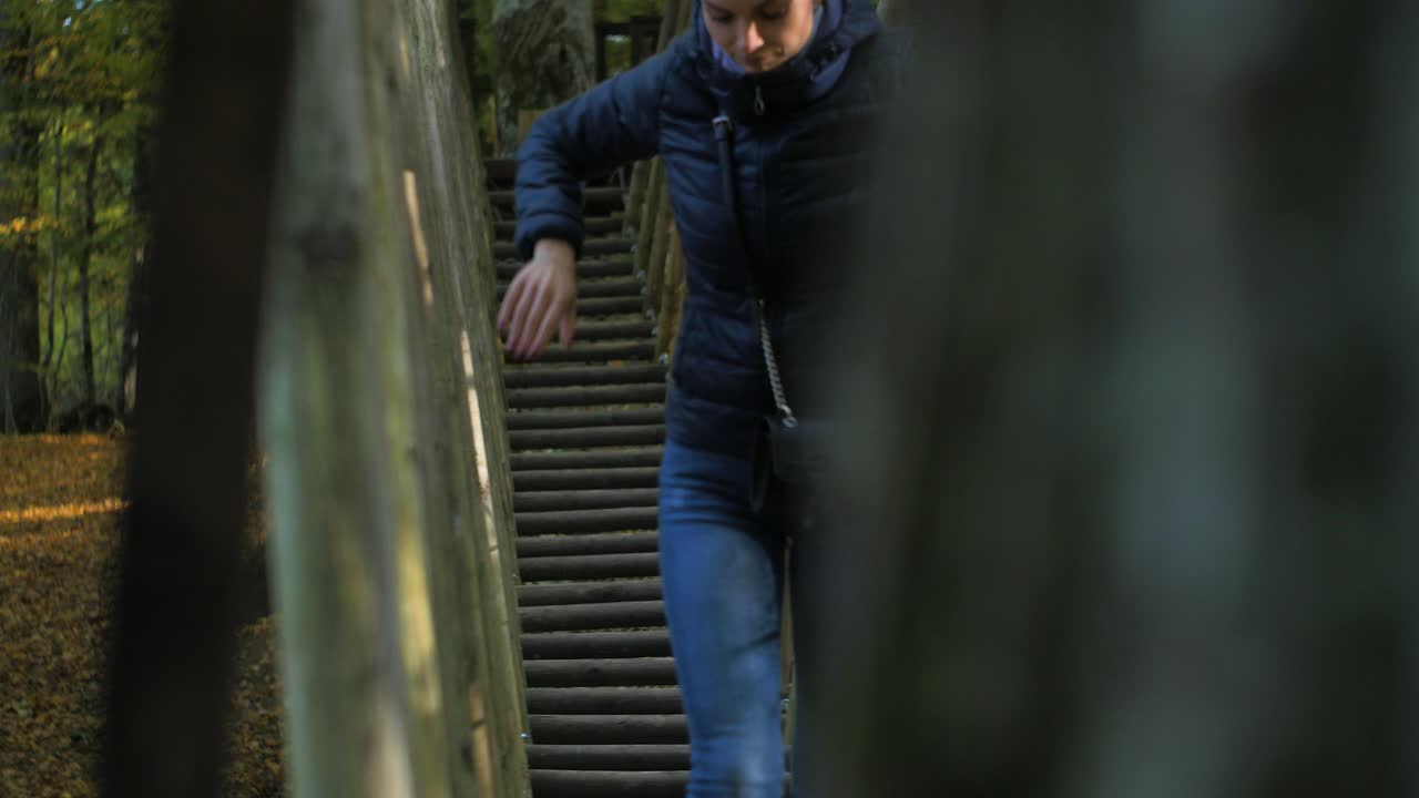 chica trepa por el puente de cuerda en un día soleado de otoño