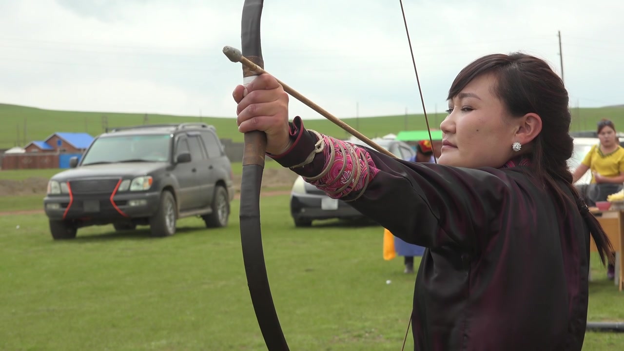 Donna mongola che pratica tiro con l'arco tradizionale in un campo aperto