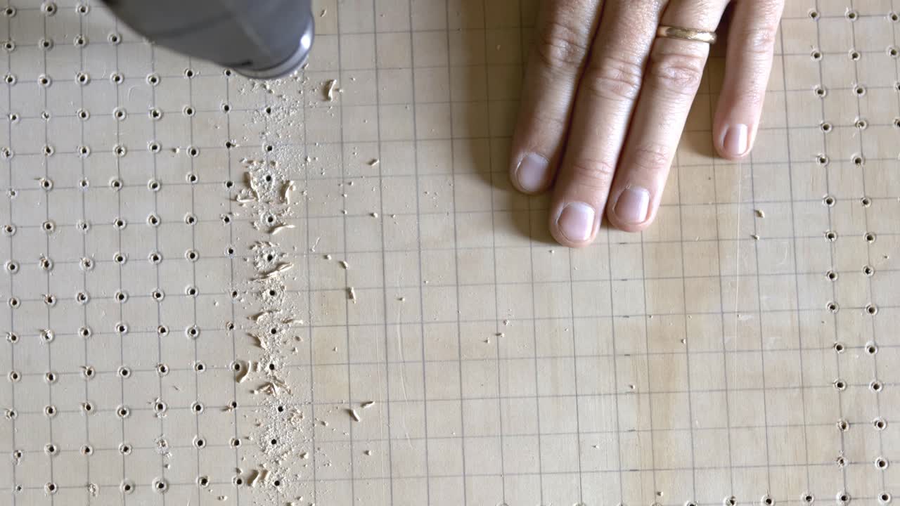 전동 공구를 사용하여 격자선에 따라 구멍 패턴을 뚫습니다.