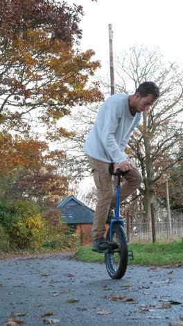 Rider performing tricks on a unicycle outdoors during autumn, showcasing balance and skill