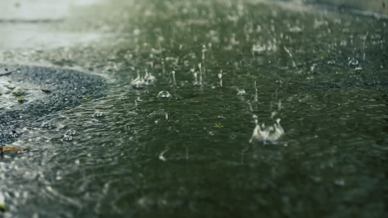 Raindrops splash on the ground. Raindrops falling into a puddle. Water splash