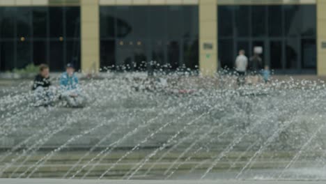 skateboarder performing trick near fountain in city