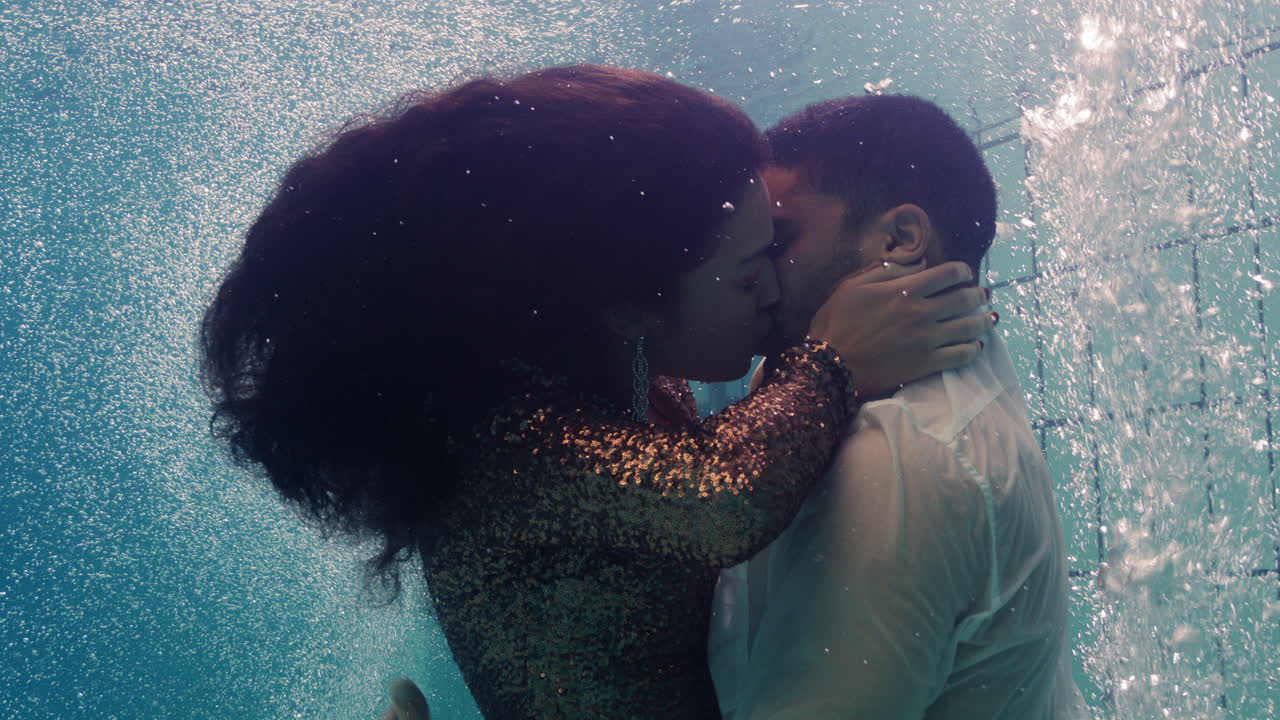 coppia romantica che si bacia sott'acqua in piscina con i vestiti giovani innamorati che si godono un bacio intimo amanti sommersi nell'acqua che galleggiano con bolle in un'intimità passionale