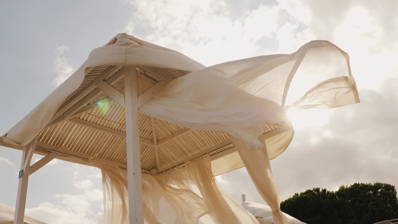 바가 리조트에서 다가오는 폭풍 - 강한 바람이 리조트의 해변 선베드에 색 가노피 천을 개발합니다.