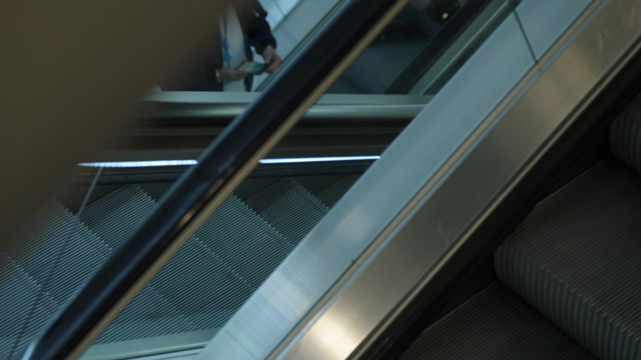Escalones y pasamanos de metal de una escalera mecánica en movimiento en un espacio público interior moderno