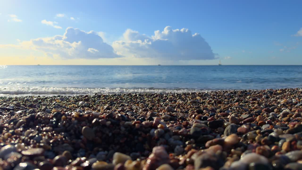 모래 해변과 작은 돌은 작은 파란 하늘의 파도와 함께 느린 움직임