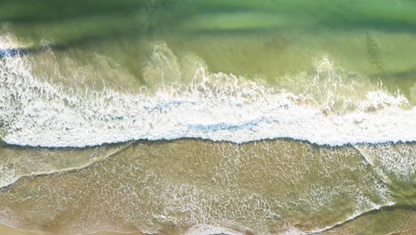 Beautiful-aerial-cinematic-top-view-of-waves-in-a-brazilian-beach-with-emerald-clear-water-at-golden-hour