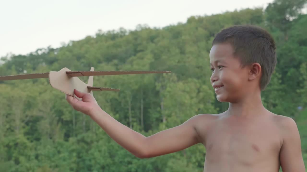 Child Playing with a Cardboard Airplane Outdoors