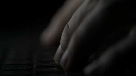 close-up of hands typing on a laptop keyboard at night