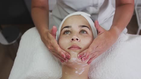 caucasian woman lying back while beautician gives her a facial