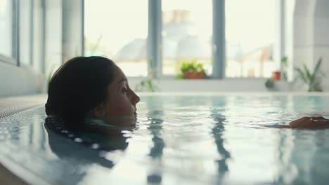 a young woman is seen in a pool, relaxing after a swim