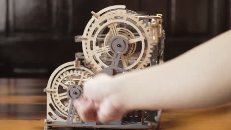 hand moving wooden gears of a toy machine with hand crank