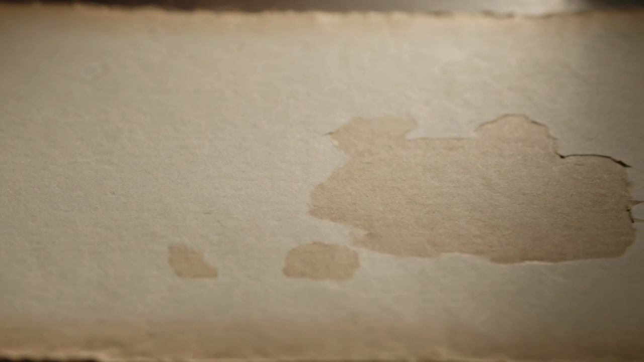 Shifting camera adjusting focus moving frame in closeup, exposing paper water stain and torn edge