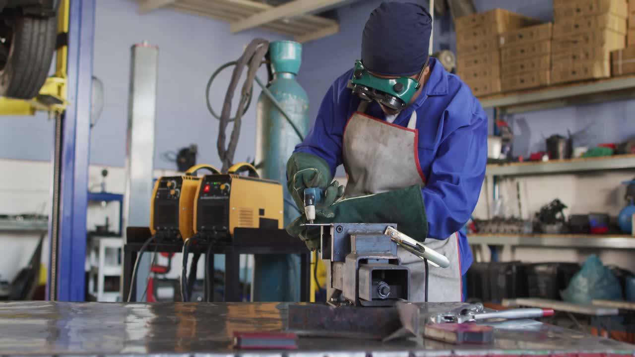 Video of african american female car mechanic using grinder, preparing car parts