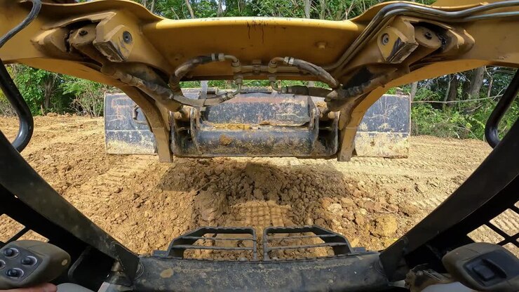 POV while operating a skid steer loader to move excess dirt to the tree line at a land development site-1