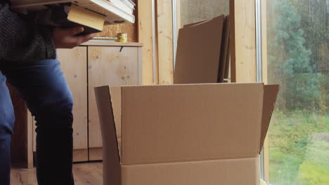 Man-inside-the-room-brings-a-stack-of-books-in-his-arms-and-puts-them-in-a-cardboard-box