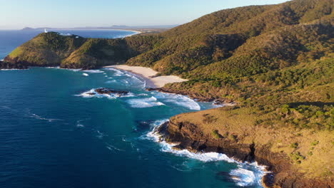 Wide-rotating-drone-shot-of-North-Smoky-Beach,-with-the-Smoky-Cape-Lighthouse-in-background