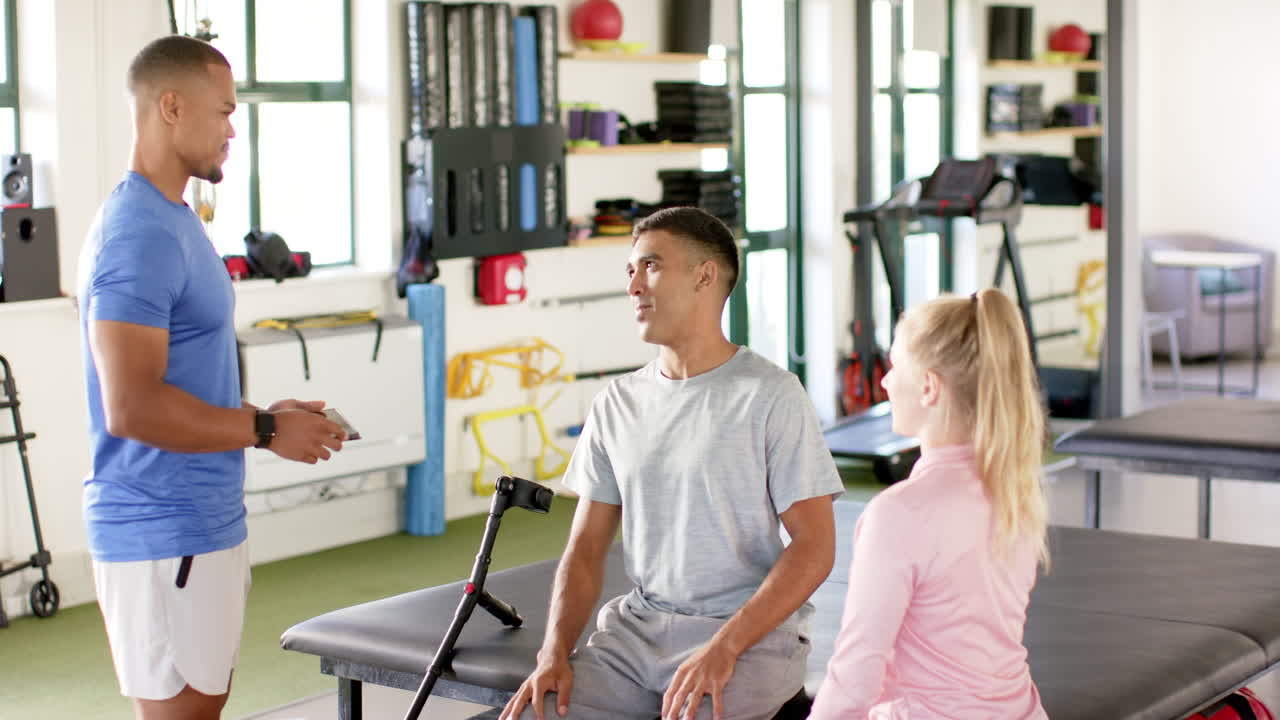 Rehabilitation session in gym, man with disability talking with therapists