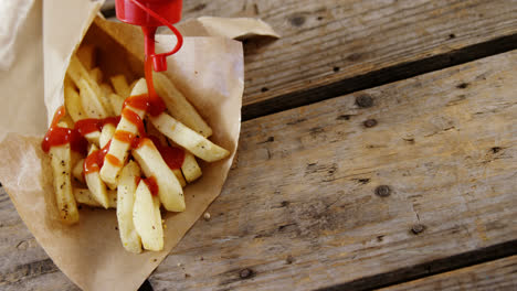 ketchup siendo exprimido sobre patatas fritas francesas en la bandeja