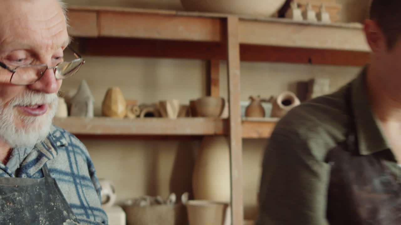 aprendiz femenina trabajando con arcilla con la ayuda de un escultor sénior