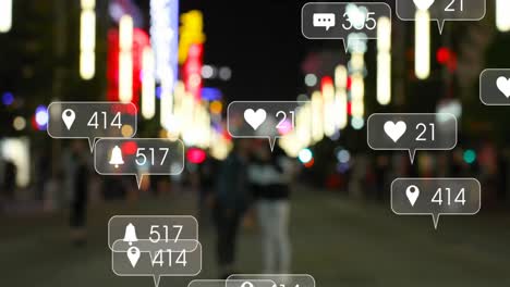 Animation-of-social-media-icons-against-blurred-view-of-people-walking-on-the-street-at-night