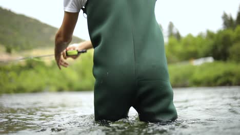 toma en cámara lenta de un pescador que usa vadeadores mientras pesca con mosca-1