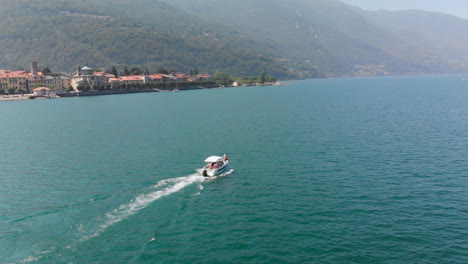 Luftaufnahme-Eines-Bootes-Auf-Dem-Lago-Maggiore-Mit-Der-Schönen-Stadt-Cannobio-Im-Hintergrund,-Italien