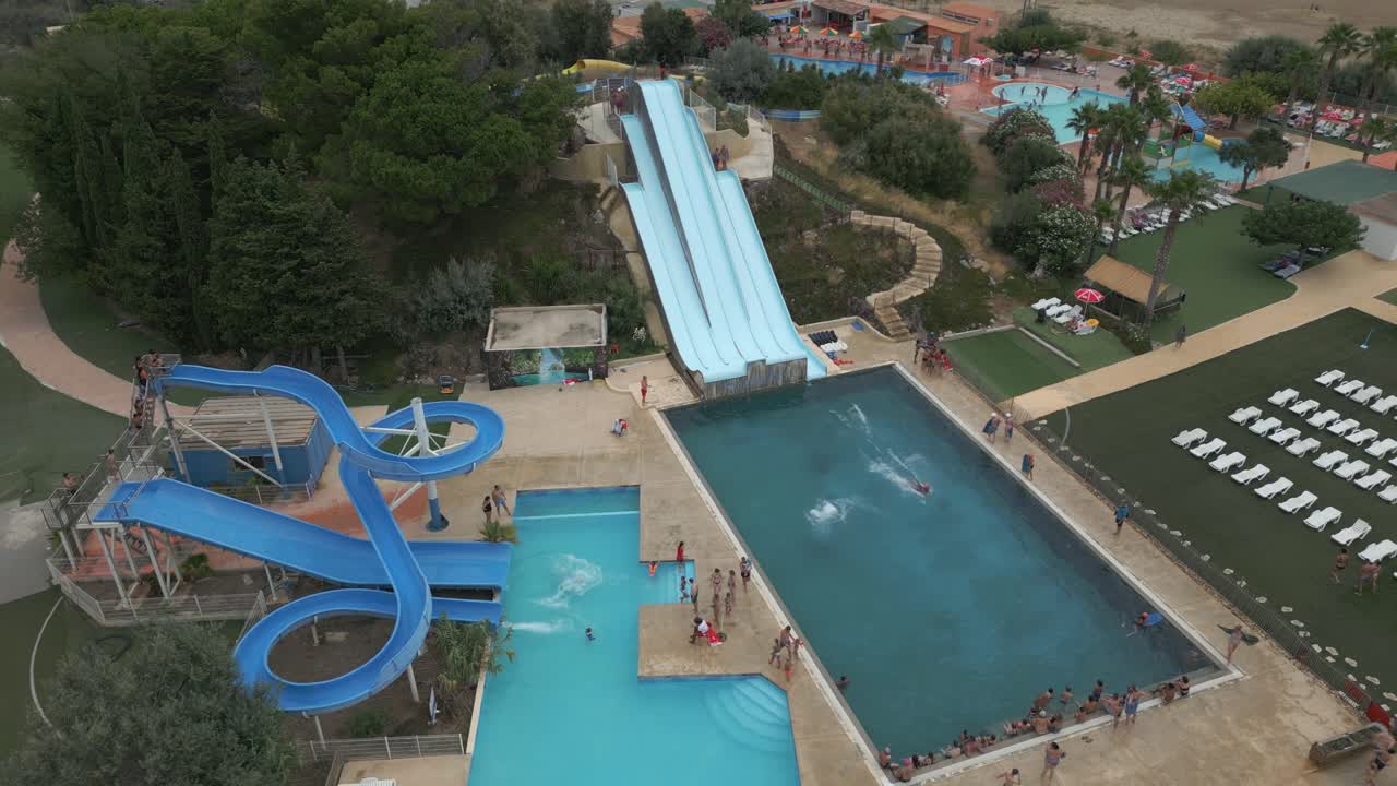 Families enjoy a summer day at a lively water park featuring thrilling slides and a spacious pool area. Laughter fills the air as kids splash around