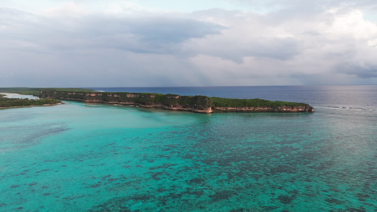 Ampio panorama aereo della baia di Lekini, Ouvéa, Nuova Caledonia, che mostra le acque turchesi della barriera corallina e la vegetazione lussureggiante dell'isola