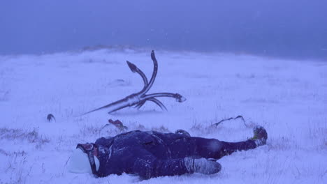 woman in snowstorm falls on her back on snowy ground, stable medium shot