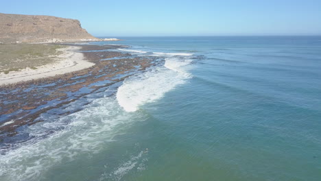 dramatic aerial of surfing along coast in south africa