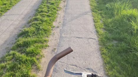 vista del volante de una bicicleta en movimiento con la carretera de asfalto debajo de ella.