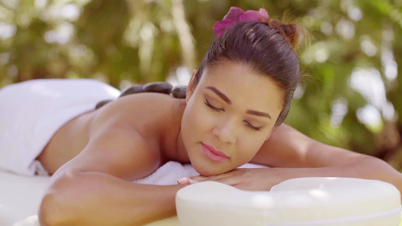 뜨거운 돌 마사지를 받는 행복한 젊은 여성