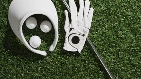 close up of golf club, balls, glove and peaked cap on grass, copy space, slow motion