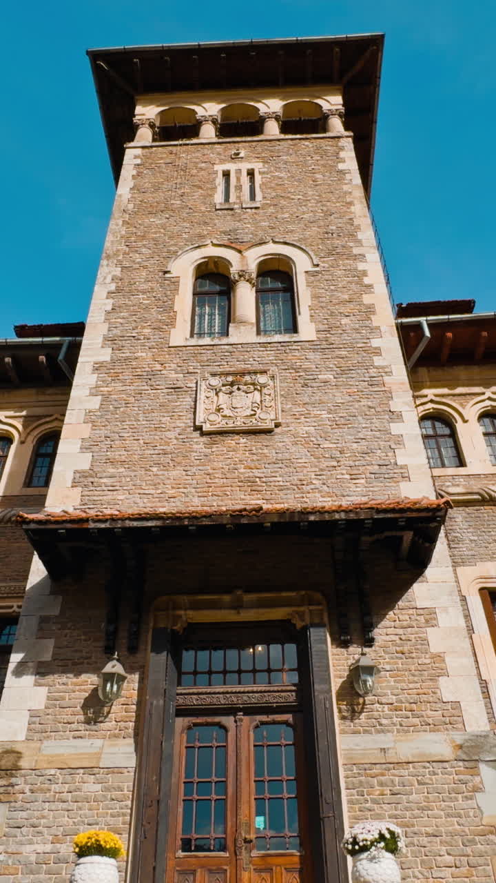 At the staircase to the old beautiful palace with tower. Cantacuzino Castle in Busteni, Romania on sunny day. Low angle view. Vertical video