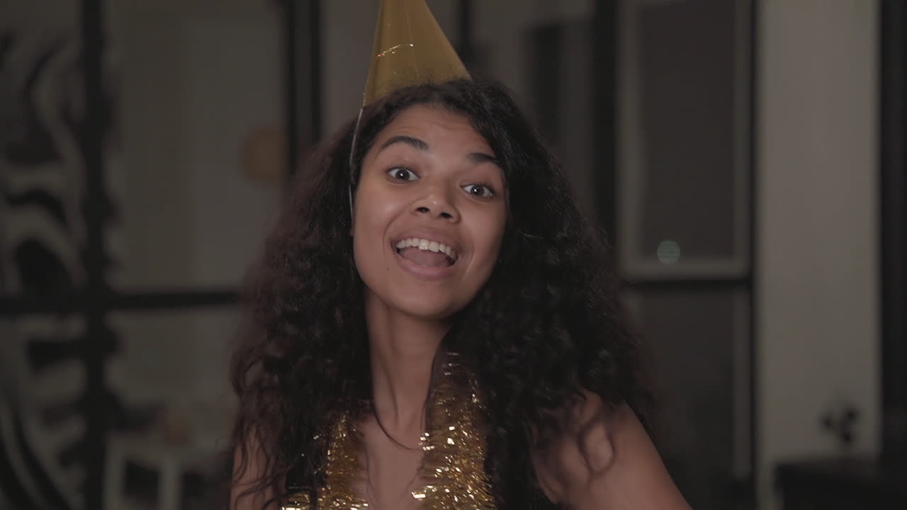 Ritratto di una graziosa ragazza di colore che fa facce buffe, balla e lancia coriandoli a una festa di Natale