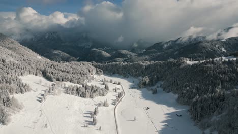 Aerial-drone-view-flying-over-picturesque-mountain-ridge-snowy-landscape-with-snow,-sunlight-and-blue-sky