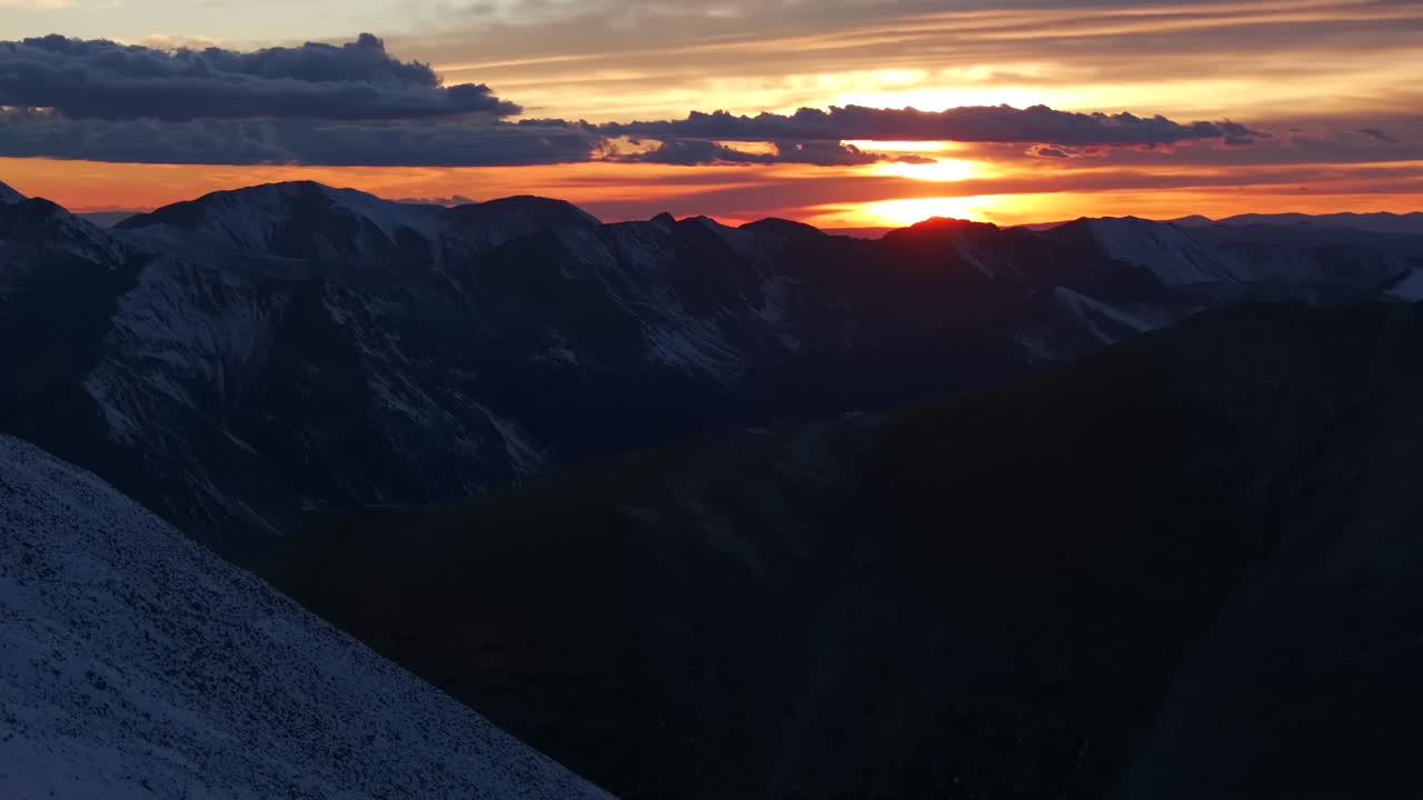 Glowing Rocky Mountains sunset Mt Mount Shavano Elbert Huron La Plata Tabeguache Antero Peak Colorado aerial drone fall autumn snow Sawatch Range top of summit sun on horizon clouds forward pan up